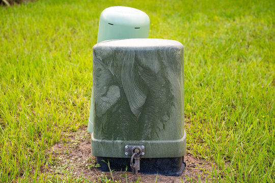 Outdoor green utility pedestal box in residential neighborhood used for telecommunications, cable, and electrical infrastructure.