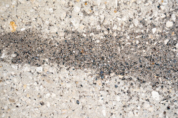 High-resolution close-up of rough concrete pavement with visible aggregate stones, useful as an abstract background or texture.