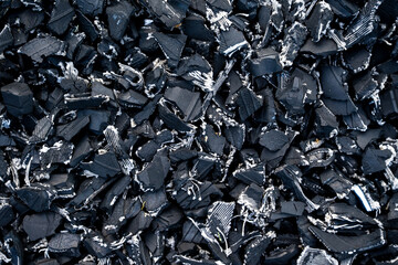Detailed close-up of shredded black rubber tire material, showing recycled texture for industrial and environmental concepts.