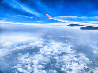 Fototapeta premium Bright blue sky with fluffy clouds viewed from an airplane window during daytime travel