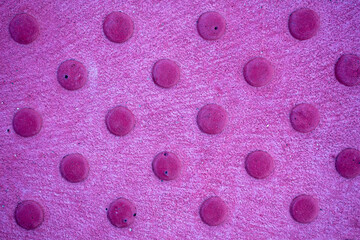 Close-up of textured tactile paving with raised circular bumps on a purple surface. Useful for accessibility, mobility safety, backgrounds, and abstract patterns.