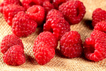 Fresh ripe raspberries with lush green leaves on a textured napkin