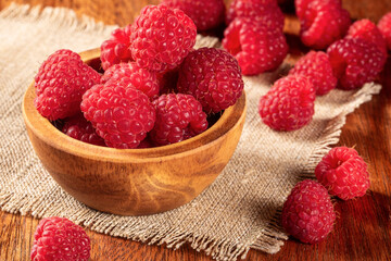 Vibrant ripe raspberries with green foliage on a cozy kitchen table