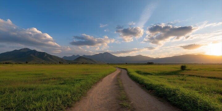 Scenic sunset over mountainous landscape with dirt road and vast green field - Powered by Adobe