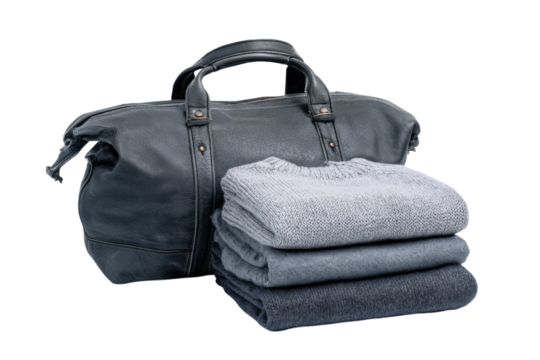 Travel essentials stylish bag with folded sweaters indoor close-up