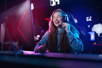 Young caucasian female gamer talks to subscribers and streaming enthusiast engaged in intense video...