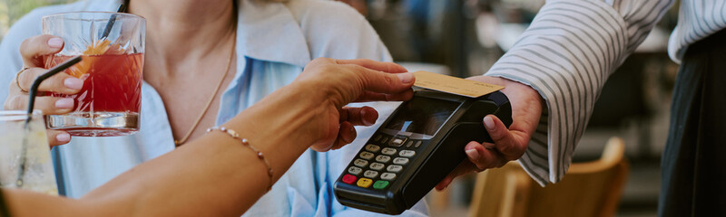 Website banner of Caucasian young adult woman holding drink while paying with credit card using...