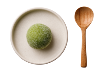 Pale green sphere on small white plate, wooden spoon