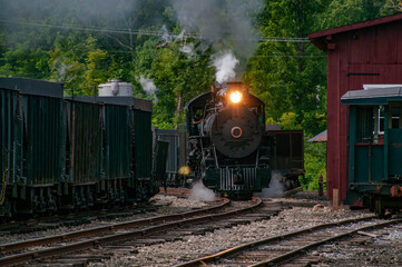 A vintage steam locomotive powers through a wooded landscape, billowing smoke against the serene...