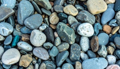 Close-up view of a textured and colorful collection of smooth pebbles, showcasing a variety of shades of gray, blue, brown, and beige.