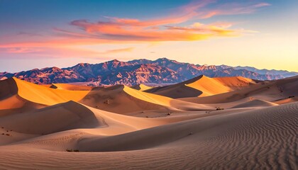 Fototapeta premium Vast dunes stretch across the desert landscape, bathed in the warm hues of a vibrant sunrise, with majestic mountains rising in the distance.