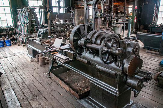 A vintage workshop filled with various tools and machinery showcases an industrial lathe in working condition.