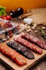 Assorted gourmet sausages sliced and vacuum packed on rustic wooden background with spices