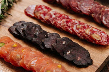 Close-up of gourmet sliced sausage with nuts on wooden board, traditional cured meat snack