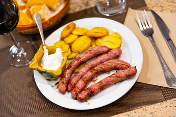 Fried sausage butifarra and potatoes are complemented with bowl with hot sauce garlic-olive alioli. Traditional Spanish dish, gastronomic novelties and discoveries.