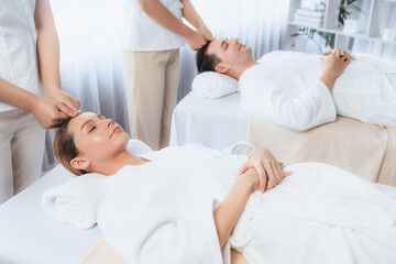 Fototapeta premium Caucasian couple enjoying relaxing anti-stress head massage and pampering facial beauty skin recreation leisure in dayspa modern light ambient at luxury resort or hotel spa salon. Quiescent