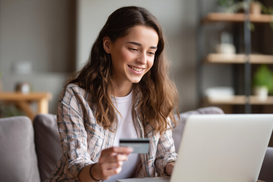 Smiling woman using laptop and credit card for online shopping at home