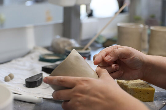 Female hands mold a clay cup in a pottery workshop