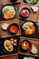 Assorted traditional meals served on wooden trays in cozy rustic setting, top view