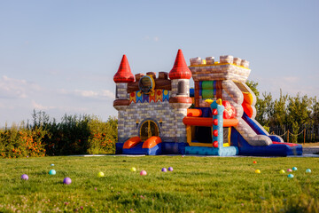 Fun and colorful inflatable castle bounce house in a grassy field on a sunny day
