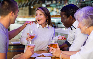 Diverse people happy talking and drinking beer at a bar table