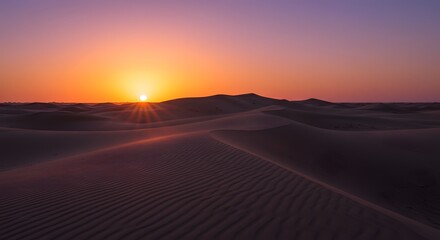 Fototapeta premium Desert horizon ablaze as the sun dips below the dunes, painting the sky in vibrant orange and purple hues.