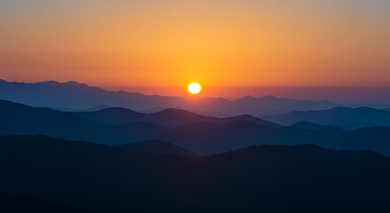 Obraz premium Stunning sunrise paints the sky with vibrant colors over majestic mountain ranges in a serene landscape