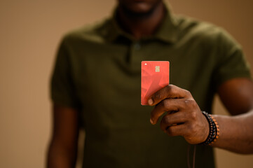 Close-up of a Nigerian man holding a debit card in his hand, with focus on the card and blurred...