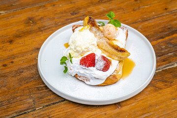 Delicious dessert with ice cream, bananas, and strawberries on a plate, ready to eat now!
