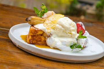 Delicious French toast dessert with ice cream, fruit, and syrup on a white plate ready to eat