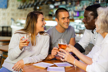 Happy diverse people drinking beer and eating tapas while spending time together in a bar