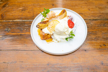 Delicious gourmet dessert with bananas, ice cream, and fresh fruit on a white plate