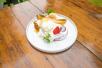 Delicious dessert plate with ice cream, berries, and caramelized bananas on wooden table