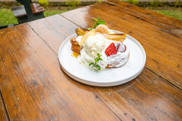 Delicious French toast with whipped cream, strawberries, bananas, and ice cream on a white plate
