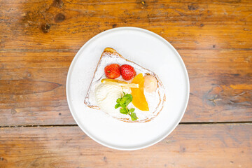 Delectable French toast dessert with fresh fruit, ice cream, and mint on a white plate