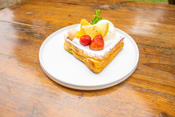 Delicious dessert with fresh fruit, ice cream, and powdered sugar on a white plate