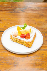 Delicious gourmet French toast with fresh fruit, cream, and mint on a white plate