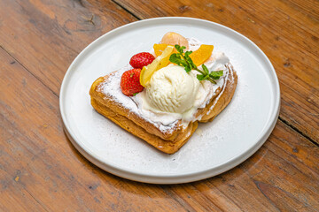 Delectable French toast with fresh fruit, powdered sugar, and ice cream on a white plate