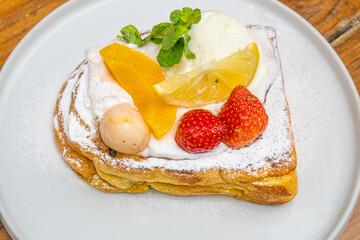 Delicious French toast dessert with fresh fruit, whipped cream, and powdered sugar on a plate