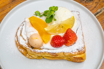 Delicious gourmet dessert with fresh berries, ice cream, and fruit slices on a white plate