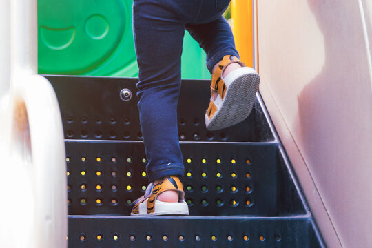 Lower part of baby feet boy in casual shoe walking up the stairs of a playground at the park, child lifestyle successful concept.
