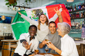 Happy international sport fans waving mexico flag while watching football match and drinking beer...