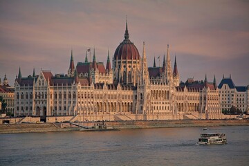 Obraz premium Hungarian Parliament Building and tourist boat on the Danube River at sunset, Budapest, Hungary