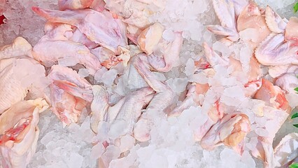 Fresh raw chicken wings displayed on a bed of crushed ice for sale at a market.