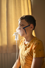 Boy using a nebulizer inhaler at home. Concept of medical treatment for asthma, flu or respiratory...