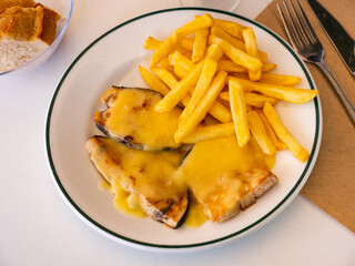 Cooked swordfish in hollandaise sauce with french fries closeup