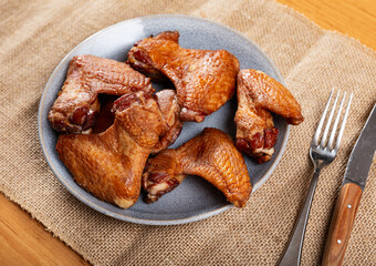 Service plate containing a lot of smoked chicken wings with necessary table laying
