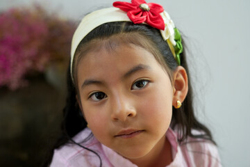 Portrait of young girl wearing a flower headband and gold earrings