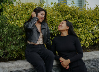 Two young women talking and smiling outdoors in urban setting