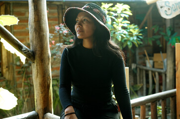 Tourist wearing bucket hat sitting and enjoying nature in wooden hut